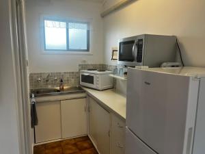 a kitchen with a white refrigerator and a microwave at Robe Nampara Cottages in Robe +7 photos