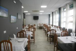 a dining room with white tables and chairs and windows at Hostal El Altet in El Alted