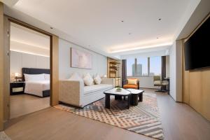 a living room with a couch and a bed and a television at Canton Hotel Guangzhou, Tapestry Collection By Hilton in Guangzhou
