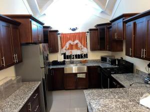 a kitchen with wooden cabinets and a stainless steel sink at Serenity Vacation Villa in Ocho Rios