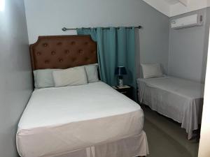 two beds in a small room with blue curtains at Serenity Vacation Villa in Ocho Rios +20 photos