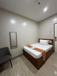 a bedroom with a bed and a chair in it at Emmie Hotel in Legazpi