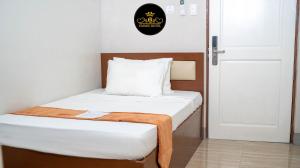 a small bedroom with a bed with a wooden headboard at Emmie Hotel in Legazpi