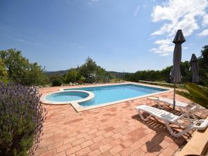 a swimming pool with two chairs and an umbrella at Delightful, authentic Quinta with pool in Loulé