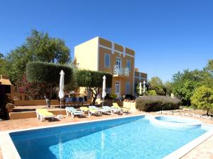a pool with chairs and umbrellas next to a building at Delightful, authentic Quinta with pool in Loulé
