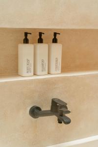 three bottles ofodorizers sitting on a shelf in a bathroom at Soma House - Adults Only in Kuta Lombok