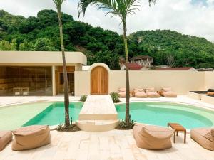 a swimming pool with palm trees in front of a house at Soma House - Adults Only in Kuta Lombok