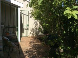 a patio with a tree and a table and a fence at On Broadwalk Cottage in Cape Town