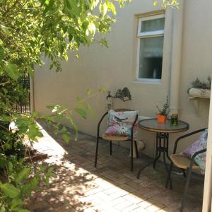 a patio with a table and chairs and a window at On Broadwalk Cottage in Cape Town