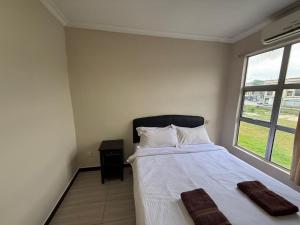 a bedroom with a bed with white sheets and a window at Jam Hotel Nilai in Nilai