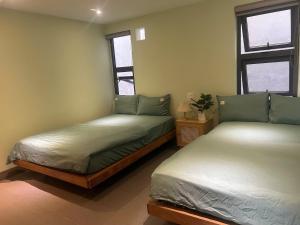 two beds in a room with two windows at Lemon House in Quy Nhon