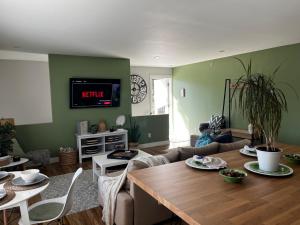 ein Wohnzimmer mit einem Tisch und einem Fernseher an der Wand in der Unterkunft Modern Maple Flat in Maple Ridge District Municipality