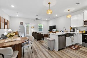 a kitchen and living room with white cabinets and a table at Biloxi Coastal Haven Walk to Beach in Biloxi