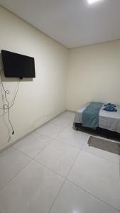 a bedroom with a bed and a flat screen tv at Vista Bela Guesthouse in Barra do Garças