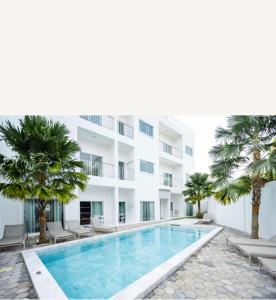 a swimming pool in front of a building with palm trees at La Cha Cha Residence in Ban Thalat Choeng Thale