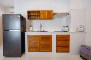 a kitchen with a black refrigerator and wooden cabinets at La Cha Cha Residence in Ban Thalat Choeng Thale