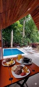 a table with plates of food on it with a pool at Cabaña Kono Rainbow Finca paraíso in Jiménez