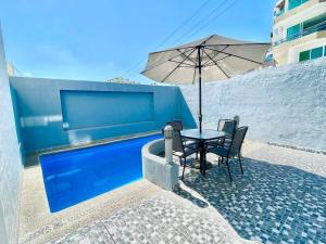 a table and chairs with an umbrella next to a pool at Comfortable apartment with pool, close to the beach in Acapulco