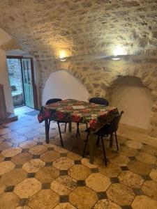 a table and chairs in a room with a stone wall at L'impasse de la courtasse in Sainte-Énimie