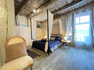 a bedroom with a canopy bed and a couch at Chambre argoitzia in Saint-Martin-dʼArberoue