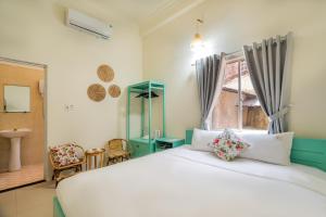 a bedroom with a large white bed and a window at Y's La House in Hoi An
