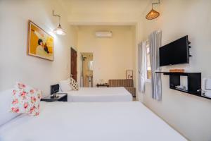 a hotel room with two beds and a flat screen tv at Y's La House in Hoi An