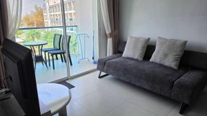 a living room with a couch and a table and a balcony at Grandblue condominium 405,406 in Ban Tha Fat