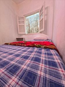 a bed in a room with a plaid blanket on it at Horizon 2 andar in Marataizes