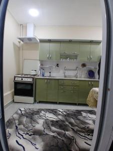 a kitchen with green cabinets and a stove at Uyut house in Samarkand