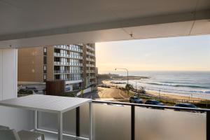 a balcony with a table and a view of the ocean at The Calm in Newcastle