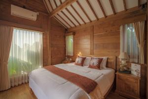 a bedroom with a bed and a large window at Jero Jawi Javanese Villa in Lebih