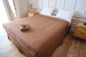 a bed in a room with a brown blanket and white pillows at Jungle Gili Air in Gili Islands