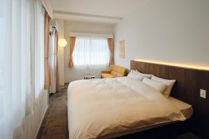 ein Schlafzimmer mit einem großen weißen Bett und einem Stuhl in der Unterkunft Arbor Onomichi in Onomichi