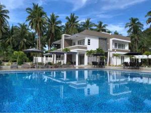 a villa with a swimming pool in front of a house at OcamOcam Sunset-Bay Guest House in Busuanga