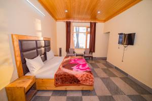 a bedroom with a bed and a tv in it at Forest Rest House Satobari in Dharamshala