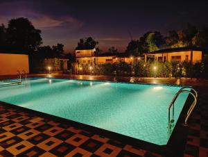 a large swimming pool at night at Bandhav Moonlight Resort in Tāla