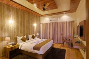 a bedroom with a bed and a desk and a television at Bandhav Moonlight Resort in Tāla