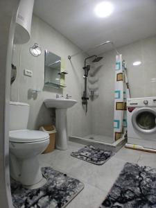 a bathroom with a toilet and a sink and a washing machine at Uyut house in Samarkand