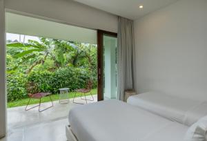 a bedroom with a bed and a balcony with chairs at Aria Villas Ubud in Ubud +56 photos