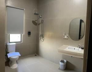 a bathroom with a toilet and a sink and a mirror at The Quadrant Hotel Ocarina Batam in Batam Center +33 photos