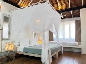 a bedroom with a canopy bed with white drapes at Trikora Beach Club and Resort in Telukbakau +47 photos