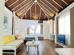 a living room with a couch and a tv at Trikora Beach Club and Resort in Telukbakau