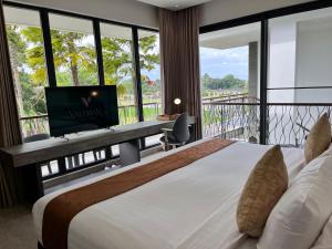 a bedroom with a bed and a desk with a television at The Valerian Villa Ubud in Ubud