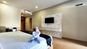 a bedroom with a bed and a tv on a wall at Nio Garden Hotel in Sumbawa Besar