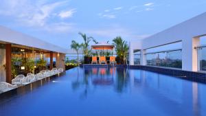 a large swimming pool in a building with chairs at Country Inns & Suites By Radisson Manipal in Manipala