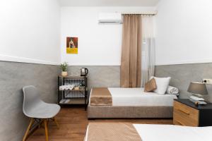 a bedroom with two beds and a chair at Budget Hotel Rooms In Yerevan in Yerevan