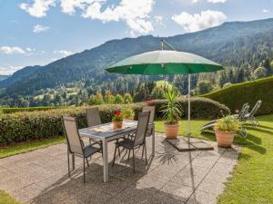 a table and chairs with a green umbrella at Apartment in Afritz near Ski Resorts in Afritz +137 photos