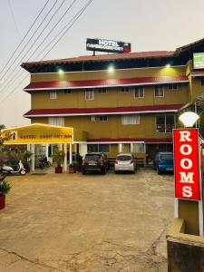 a large building with cars parked in a parking lot at Hotel caveri comfort in Madikeri