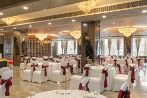 a banquet hall with white tables and chairs and chandeliers at Clarks Inn Bokaro in Bokāro