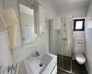 a white bathroom with a sink and a shower at Olive Depadance in Mostar